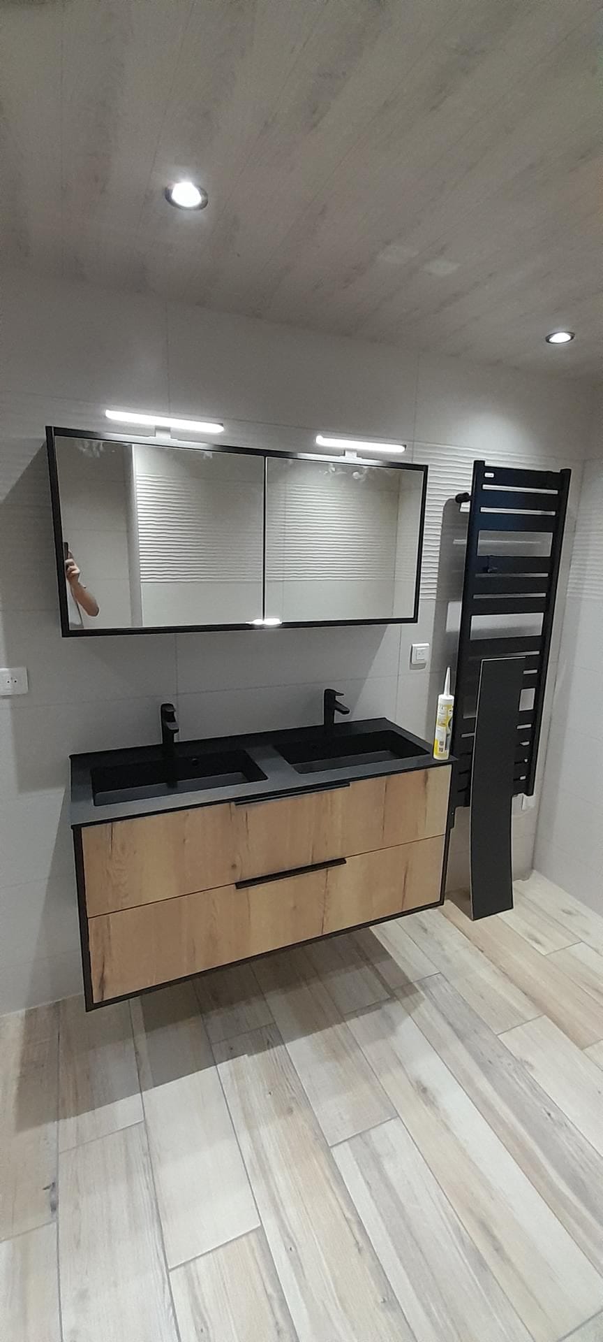 Salle de bain clé en main : double vasque noire sur meuble bois suspendu et miroir éclairé, réalisée dans le Doubs